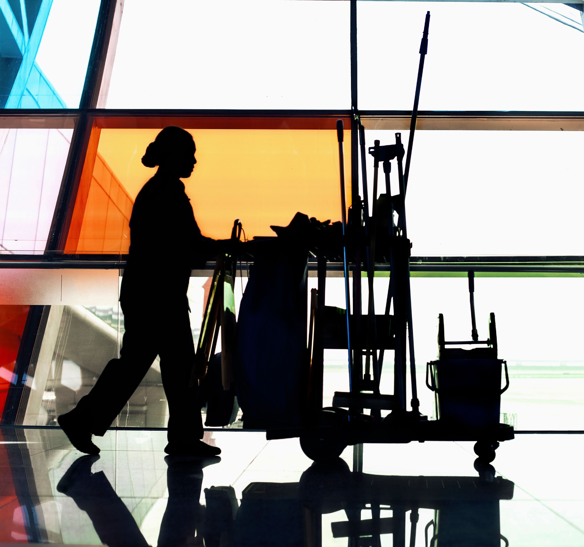 Hausmeister, der den Reinigungswagen durch den Flur schiebt, Schatten, Fokus auf Schatten, digitaler Verbundwerkstoff, volle Länge, Seitenansicht